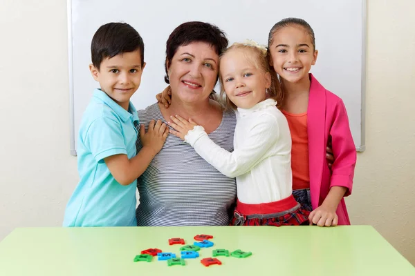 Portrait of Mature preschool teacher and children in a classroom during class