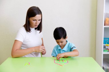 Teacher and preschool child building house on a table