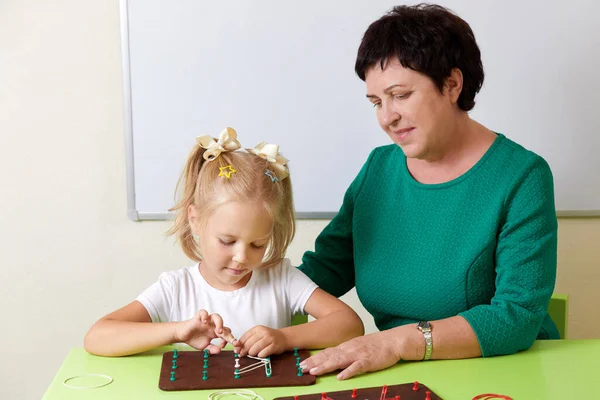 Mature woman teaches child the alphabet. Development of fine motor skills concept