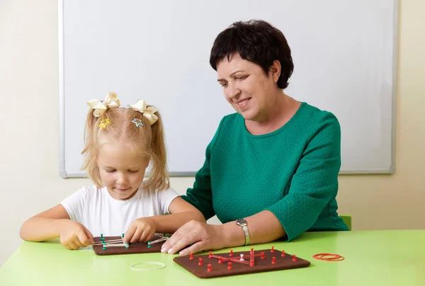 Mature woman teaches child the alphabet. Development of fine motor skills concept