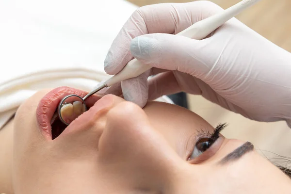 Dentist examining patient teeth with mirror in dentist clinic. Having dental checkup