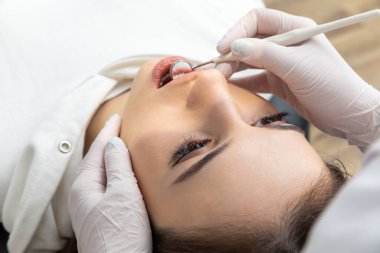 Dentist examining patient teeth with mirror in dentist clinic. Having dental checkup