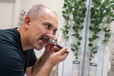 Man shaving with a razor in bathroom in the morning