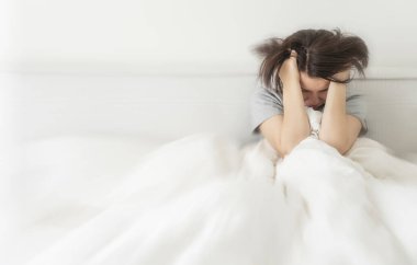 evde, yatakta beyaz keten boşaltmak için metni sola oturan genç esmer kadın