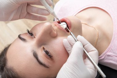 Dentist examining patient teeth with mirror in dentist clinic. Having dental checkup
