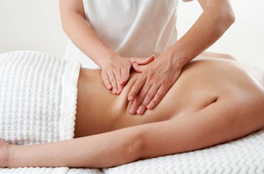 Masör masaj salonundaki masaj masasında genç bir kadına masaj yapıyor. Kaplıcada sırt masajı yaparken dinlenen genç bir kadın. Spa tedavisi kavramı