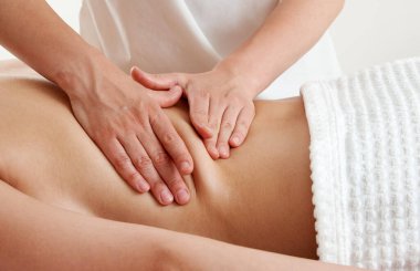 Masör masaj salonundaki masaj masasında genç bir kadına masaj yapıyor. Kaplıcada sırt masajı yaparken dinlenen genç bir kadın. Spa tedavisi kavramı