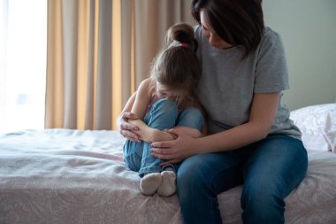 Sevgi dolu genç bir anne, üzgün küçük kızına dokunuyor, destek oluyor, genç bir anne, sevimli bir anaokulu kızını rahatsız ediyor.,