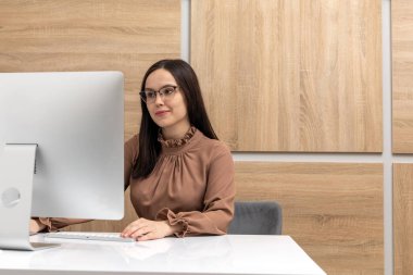 Young female secretary working in office on a computer