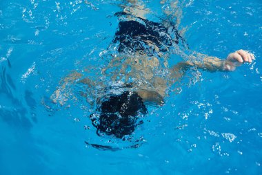 Preschool boy learning how to swim in pool