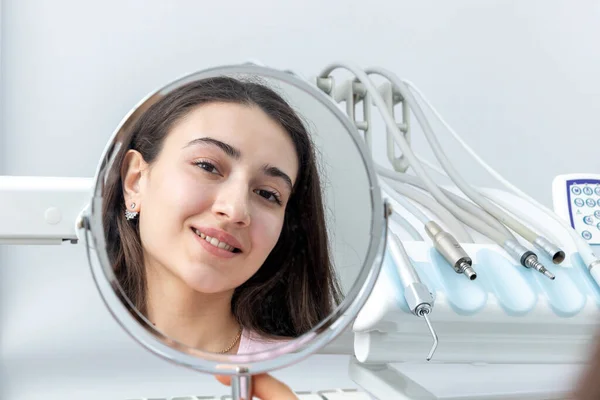 Young woman looking in a mirror after a dental procedure