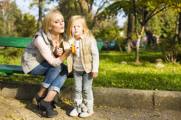 Bela mãe e filha com bolhas de sabão — Fotografia de Stock