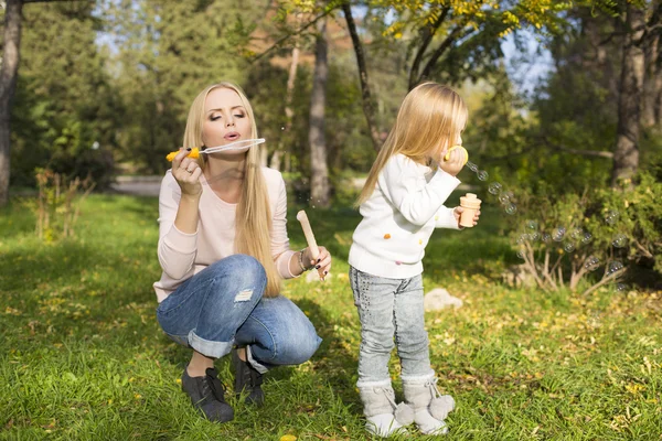 Beautiful mother and daughter with soap bubbles — Stock Photo, Image