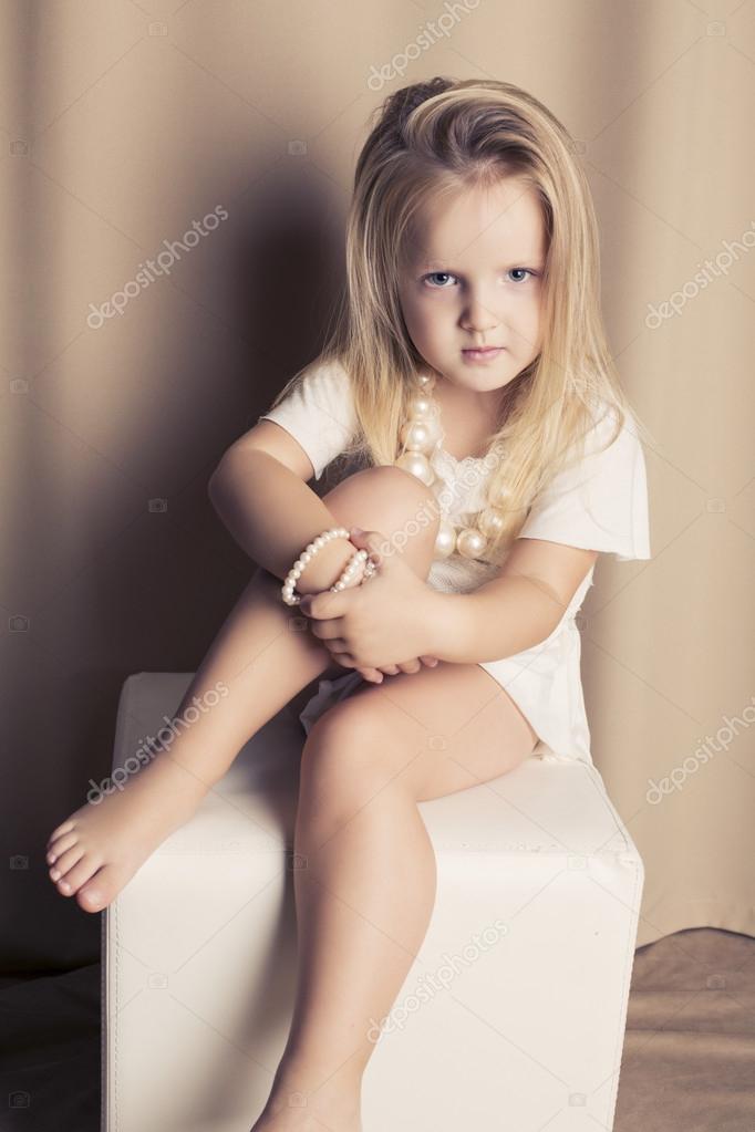 Pretty blond little girl in a white short dress Stock Photo by