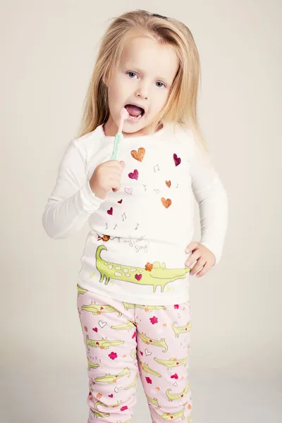 Funny little girl in pyjamas with tooth brush — Stock Photo, Image