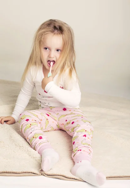 Funny little girl in pyjamas with tooth brush