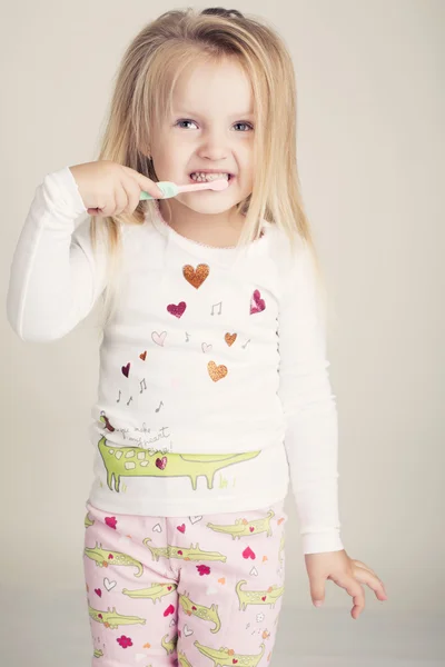 Funny little girl in pyjamas with tooth brush — Stock Photo, Image