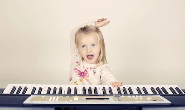 Adorable funny little girl playing in synthesizer — Stock Photo, Image
