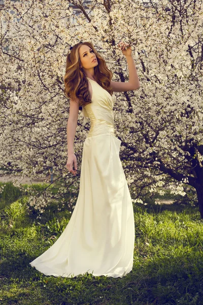 Beautiful girl with red hair posing at the spring blossom park — Stock Photo, Image