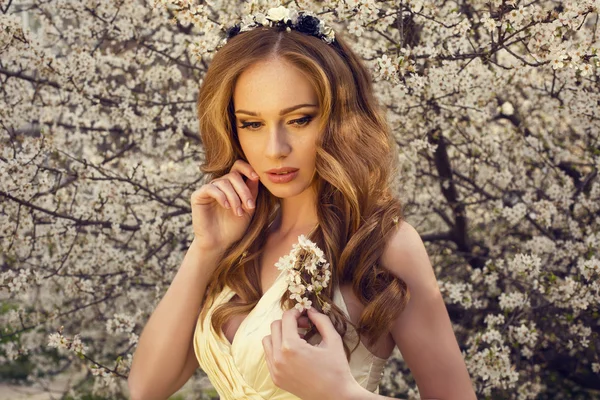 Hermosa chica con el pelo rojo posando en el parque de flores de primavera —  Fotos de Stock