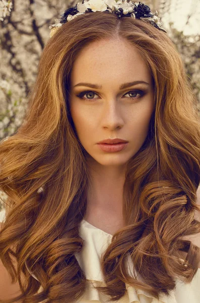 Schönes Mädchen mit roten Haaren posiert im Frühlingsblütenpark — Stockfoto
