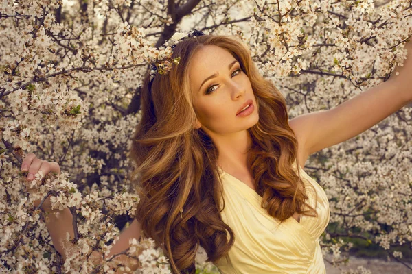 Beautiful girl with red hair posing at the spring blossom park — Stock Photo, Image