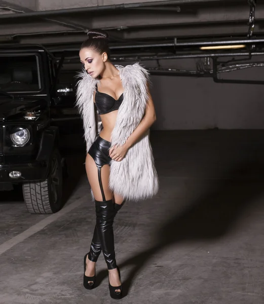 Mulher glamour sexy em lingerie e casaco de pele posando ao lado de um carro — Fotografia de Stock