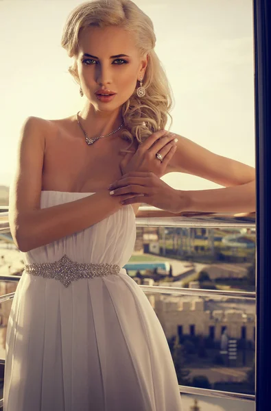 Красивая невеста с светлыми волосами позирует на балконе — стоковое фото