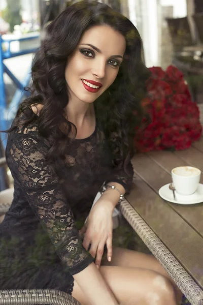 Hermosa morena sentada en el café de la ciudad con una taza de café — Foto de Stock