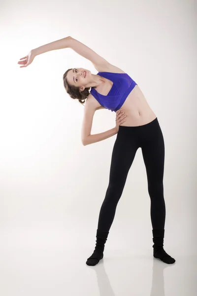 Vacker kvinna att göra stretching på vita studio — Stockfoto