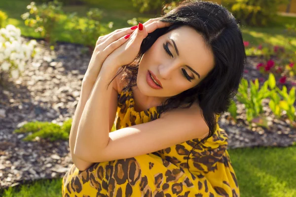 Beautiful woman with dark hair and blue eyes posing at summer garden — Stock Photo, Image