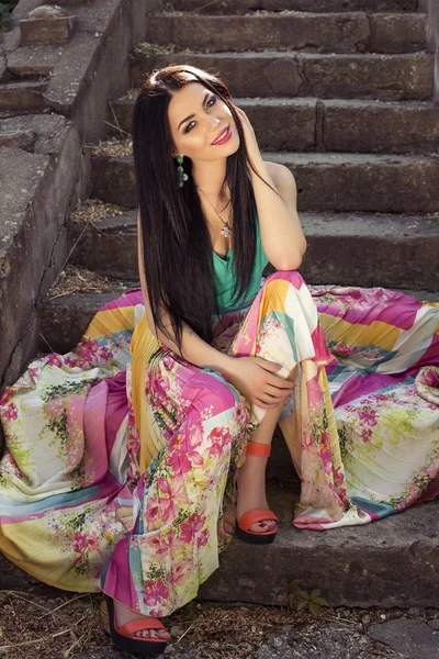 Hermosa mujer elegante en vestido colorido posando en el parque — Foto de Stock