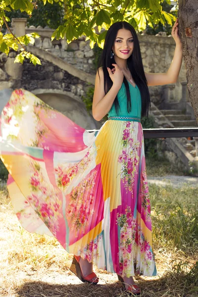 Mooie elegante vrouw in kleurrijke jurk poseren in park — Stockfoto