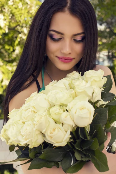 Красива дівчина з темним волоссям позує з букетом троянд — стокове фото