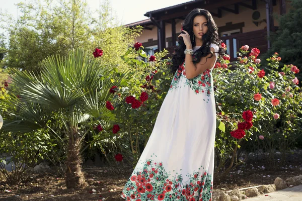 Beautiful woman in elegant dress posing at villa's garden — Stock Photo, Image