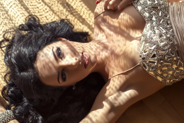 Сексуальная брюнетка в роскошном платье лежащая на деревянном полу — стоковое фото