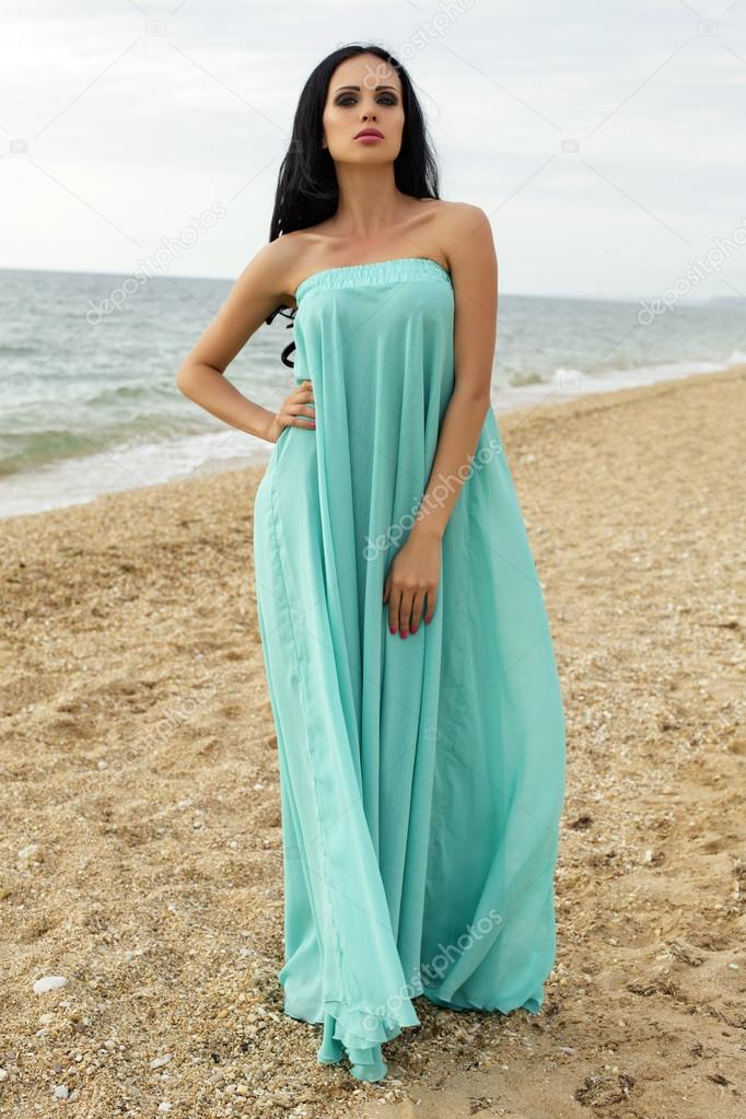 sexy beautiful woman in elegant dress posing at beach