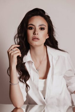 Stüdyoda poz veren zarif bluzlu, siyah saçlı güzel bir kadının moda fotoğrafı.