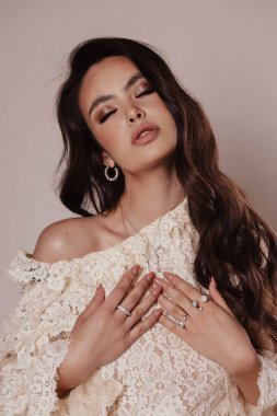 Stüdyoda poz veren zarif bluzlu, siyah saçlı güzel bir kadının moda fotoğrafı.