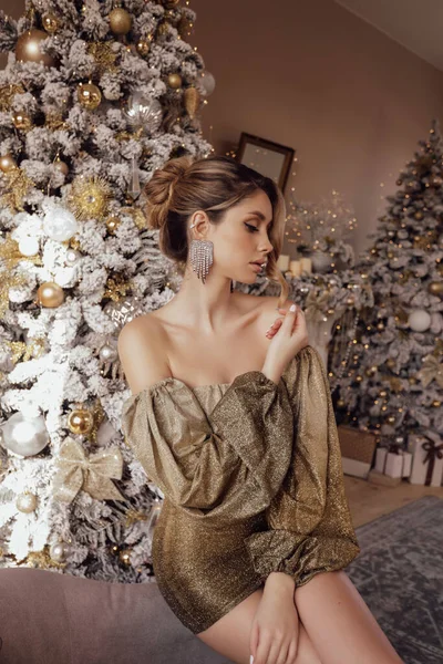 美しいです女性のクリスマス写真ブロンド髪でエレガントなドレスポーズ近くに装飾されたクリスマスツリーで居心地の良い家 — ストック写真