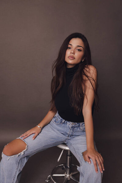 модная фотография красивой женщины с темными волосами в повседневной одежде позирует в студии
