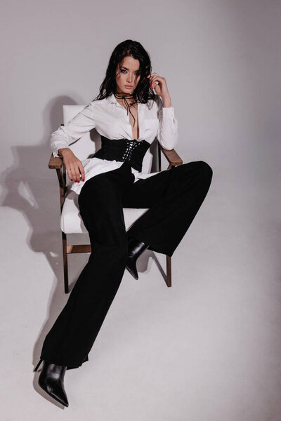 fashion photo of beautiful woman with dark hair in white shirt posing in studio
