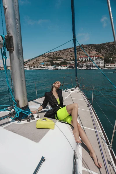 时尚的户外照片 美丽的女人穿着雅致的衣服 一头乌黑的头发 躺在海里的游艇上 — 图库照片