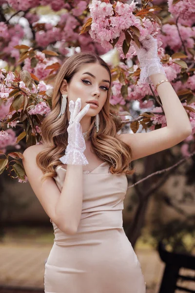 时尚的户外照片 美丽的女人 穿着雅致的衣服 在盛开的樱花花园里摆姿势 — 图库照片