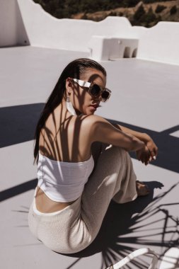 Güzel, siyah saçlı, şık elbiseli ve beyaz köşkte poz veren güzel seksi bir kadının moda fotoğrafı.
