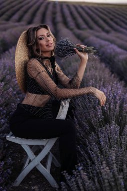 Gün batımında çiçek açan lavanta tarlasında poz veren siyah saçlı güzel bir kadının açık hava fotoğrafı.