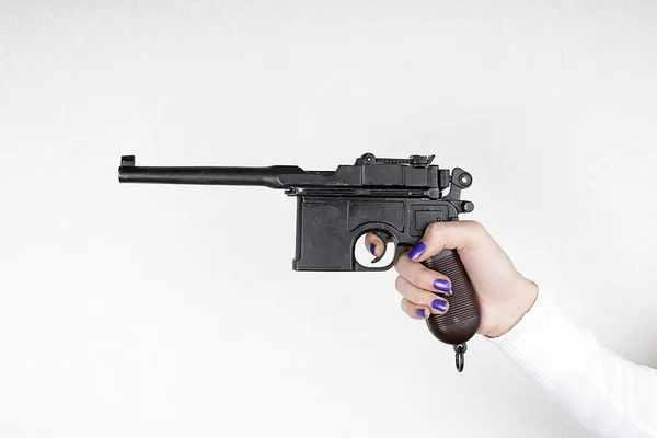 Mão segurando uma arma em um fundo branco — Fotografia de Stock