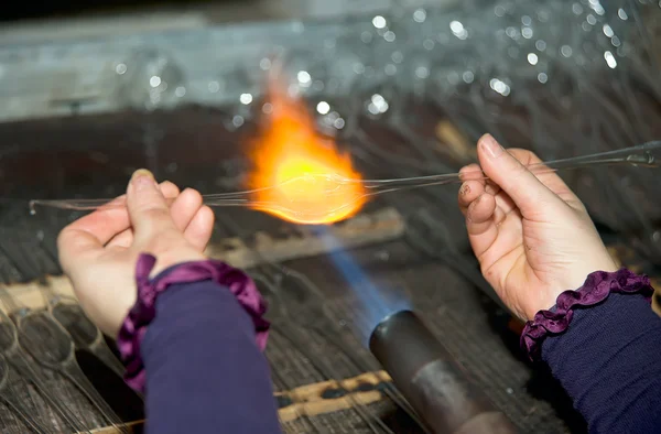 Glassblower heats the glass piece for shaping — Stock Photo, Image