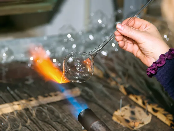 Glassblower heats the glass piece for shaping the future Christmas ornament — Stock Photo, Image