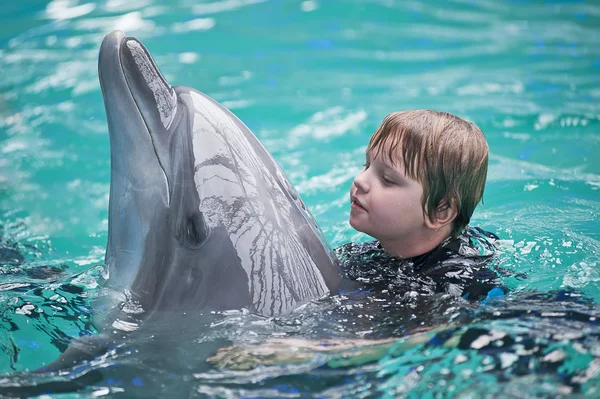 Het kleine meisje zwemmen in het zwembad met een dolfijn — Stockfoto